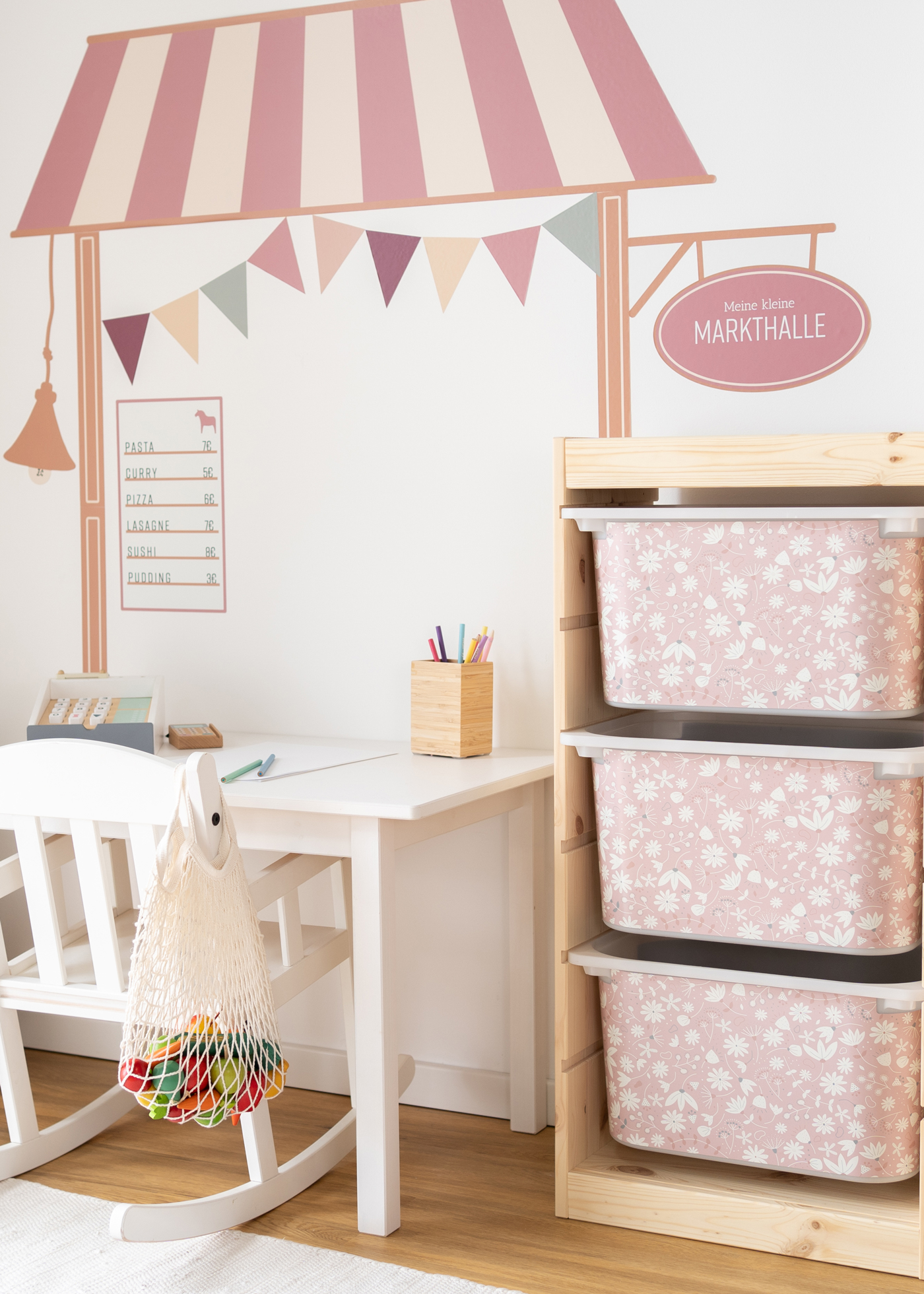 Kinderfreundliche Box im IKEA TROFAST Regal, bedruckt mit einem verspielten rosa Blumenmuster.