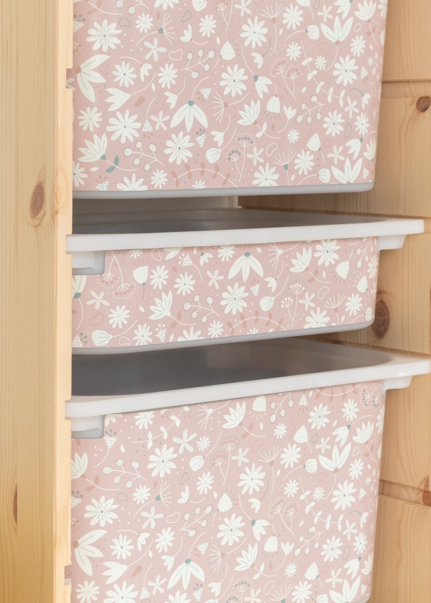 Aufbewahrungsbox mit rosa Blumendesign im IKEA TROFAST Regal Kindgerechte Aufbewahrungsbox im TROFAST Regal, verziert mit einem rosa Blumenmuster.