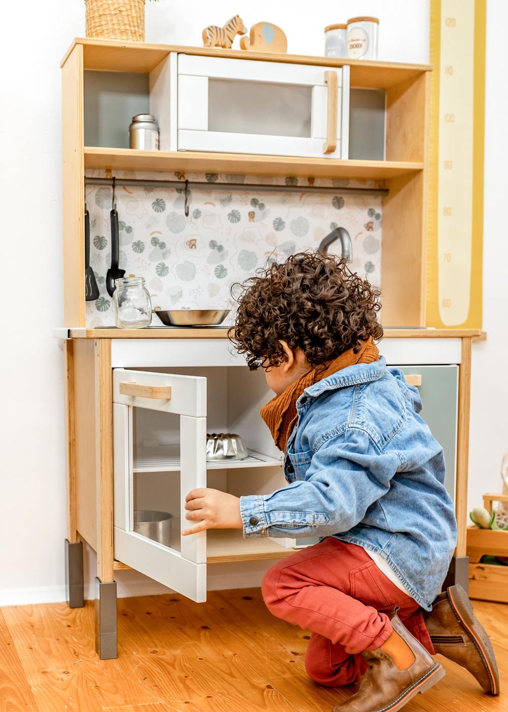 Ein Junge sitzt vor einer Kinderküche