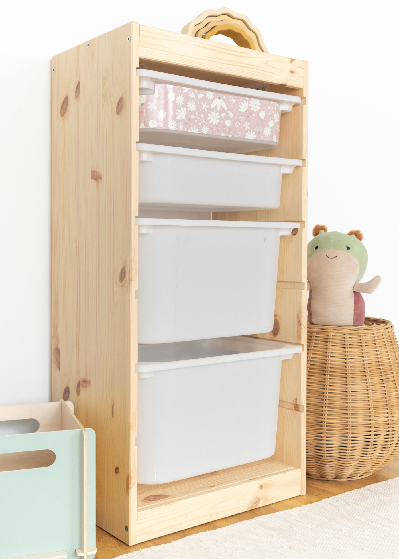 Spielzeugaufbewahrung mit rosa Blumenmuster im IKEA Regal IKEA TROFAST Regal mit Box, dekoriert mit einem eleganten rosa Blumenmotiv.
